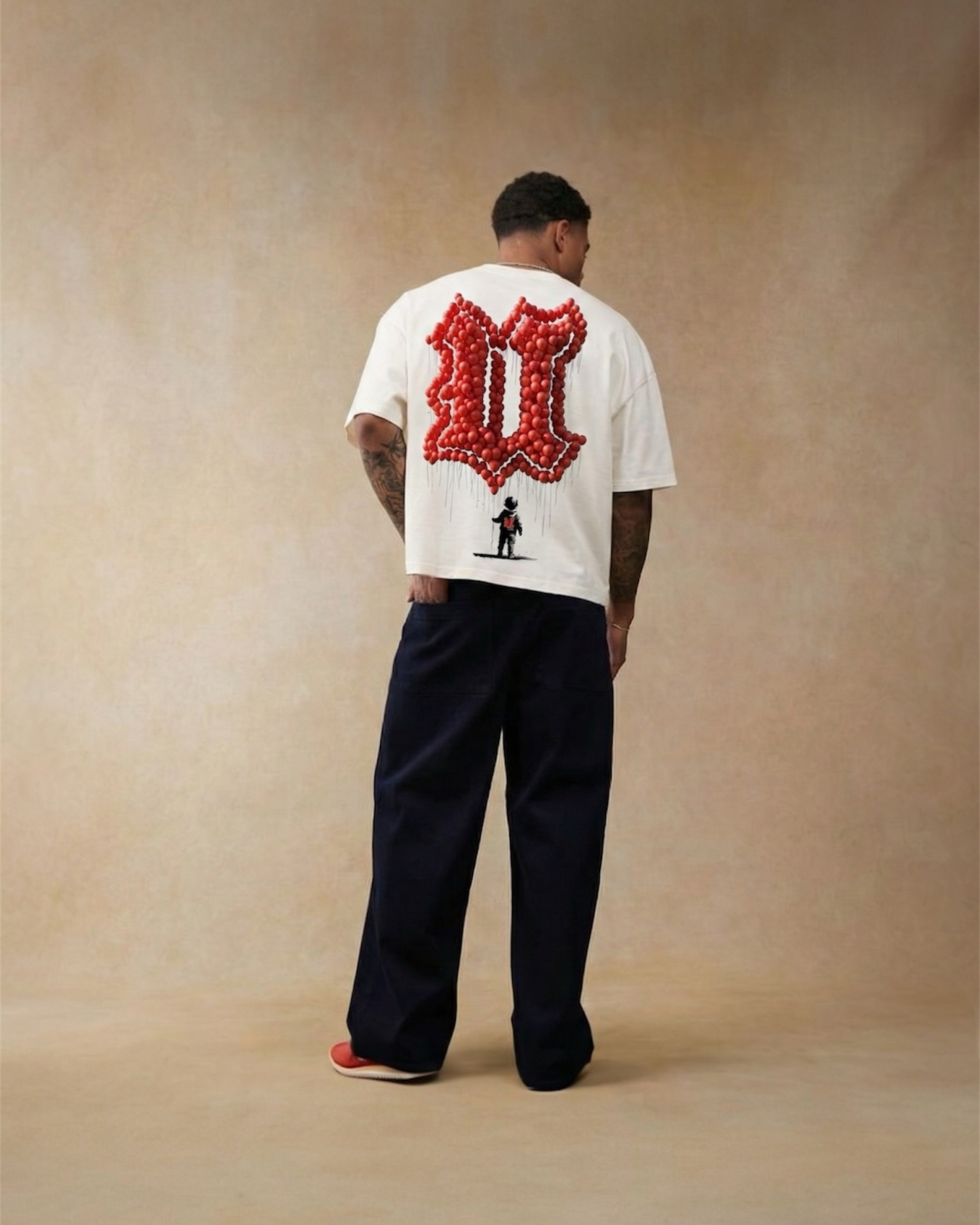 Person wearing a white t-shirt with a red graphic on the back against a beige background
