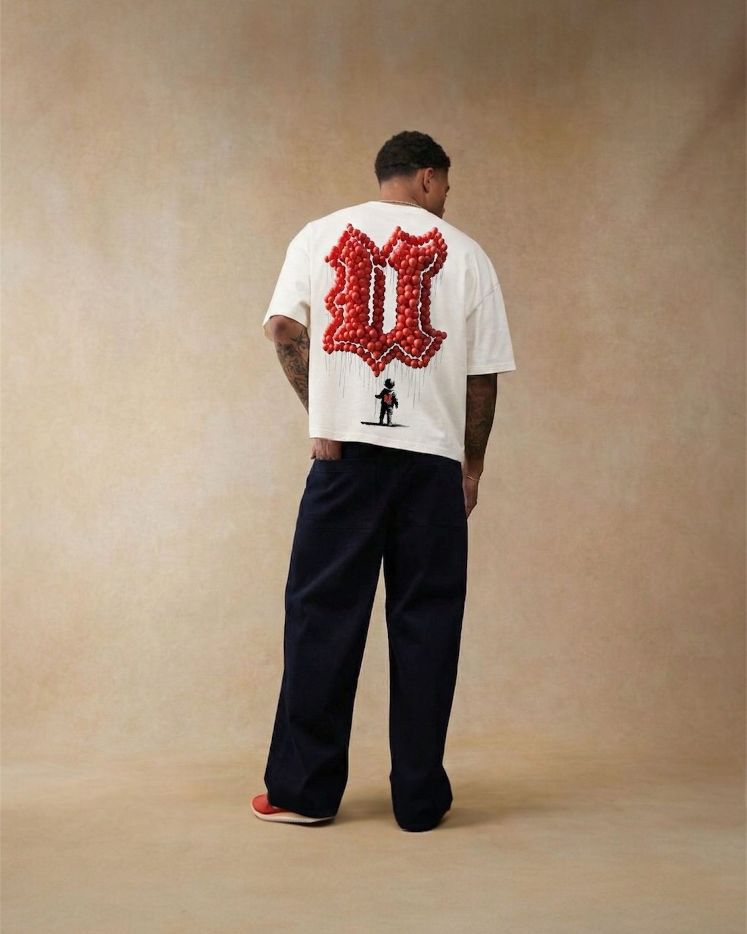 Person wearing a white t-shirt with a red graphic on the back against a beige background